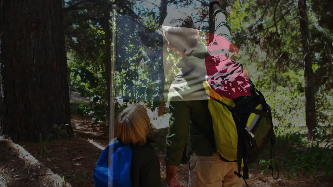 In forest, father and child with backpacks pointing at trees, exploring nature