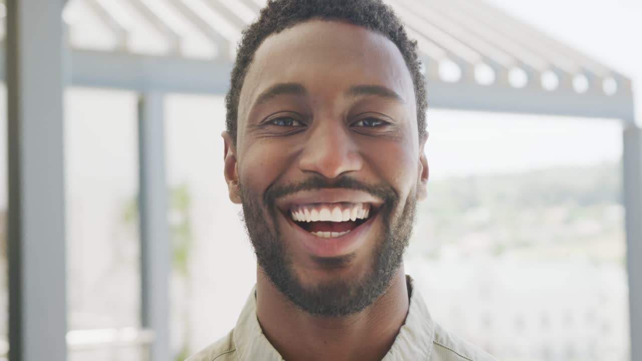 Portrait of happy african american businessman looking at camera and smiling at office, slow motion