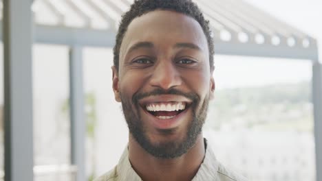 portrait of happy african american businessman looking at camera and smiling at office, slow motion