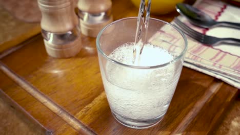 Agua-Mineral-Vertida-En-Un-Vaso,-El-Desayuno-De-La-Mañana,-Cámara-Lenta-Con-Seguimiento-De-Rotación.