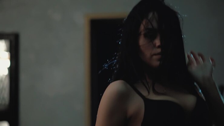 una bella ragazza in lingerie sta ballando in una stanza scura.