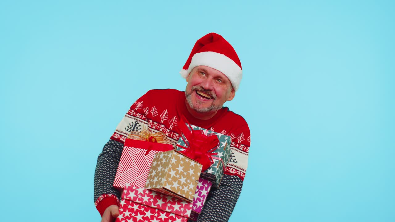 Man in christmas red sweater santa hat smiling holding many gift boxes new year presents shopping