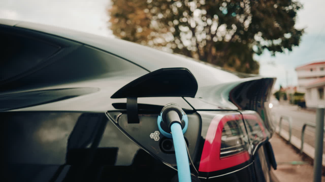 Close up view of a charging plug connected to a sleek black electric car