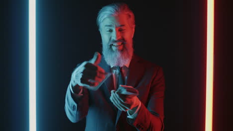 smiling businessman displaying money under neon lights