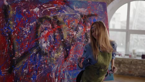 woman dancing in front of abstract painting in studio, stained cloth in paint