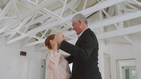 caucasian senior couple spending time together dancing in a ballroom