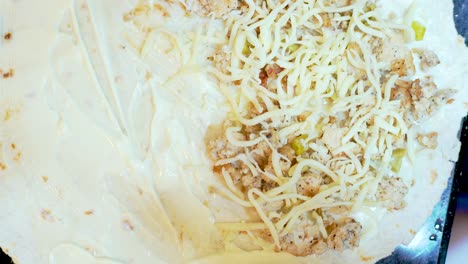 preparación de un sándwich de taco con pollo molido y queso