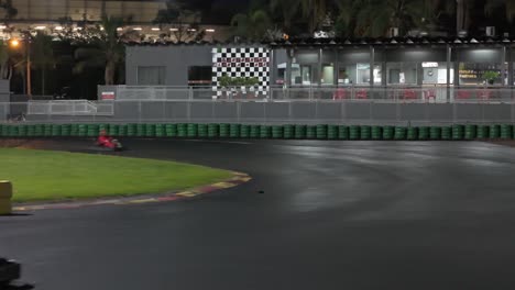 drone shot of 2 karts racing and making a turn on the track at night