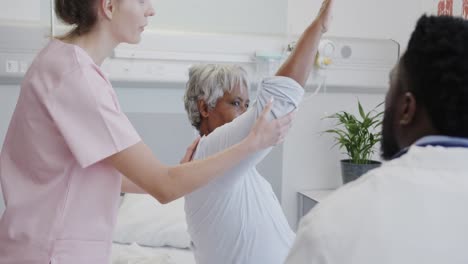 diverse male doctor and female physio treating senior female patient, slow motion