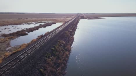 vías de tren vacías bordean un estanque en la pradera plana