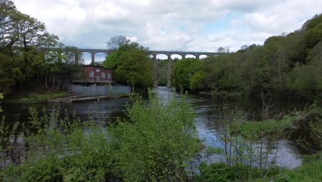 Fresh-flowing-scenic-canal-aqueduct-pump-house-woodland-countryside-aerial-rising-view-over-creek