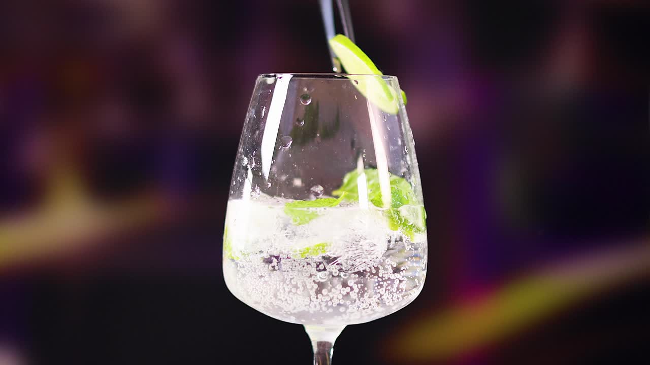 A sequence showing a mojito cocktail being prepared with lime and mint in a vibrant bar environment