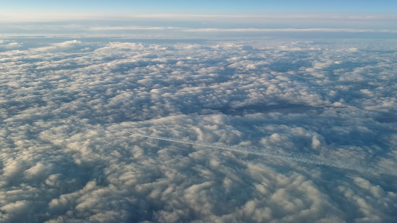 vista increíble desde la cabina de un avión que vuela alto por encima de las nubes dejando un largo rastro de aire de vapor de condensación blanco en el cielo azul