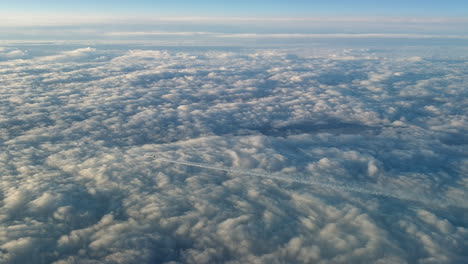 Incredible-view-from-the-cockpit-of-an-airplane-flying-high-above-the-clouds-leaving-a-long-white-condensation-vapour-air-trail-in-the-blue-sky