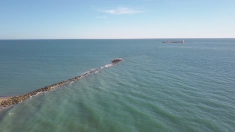 Luftaufnahme-Von-Sancti-Petri-Wellenbrecher-Mit-Burg-Von-Sancti-Petri-In-Der-Ferne-In-Chiclana-De-La-Frontera,-Spanien