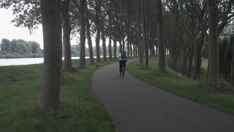 Frau-Mit-Fahrrad-Im-Park-Mit-Bäumen-Und-Gras