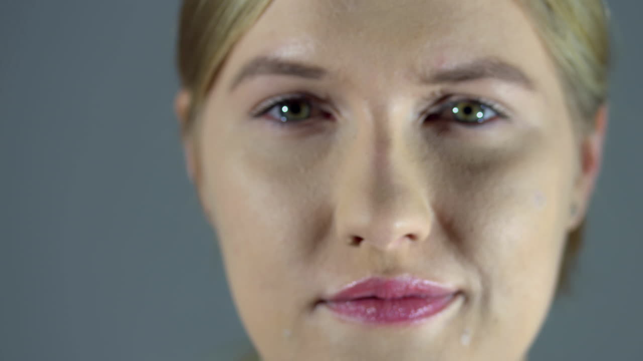 Close up shot of blurred illuminated womans face with make up getting in focus