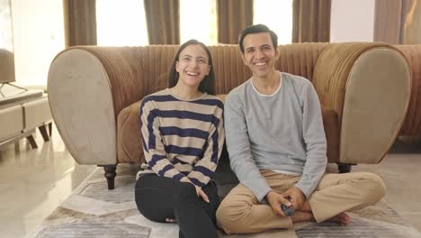 happy indian couple watching tv and laughing