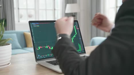 un hombre de negocios asiático con traje de negocios feliz después de ver la tendencia al alza en el comercio en la pantalla de la computadora mientras trabajaba en casa.