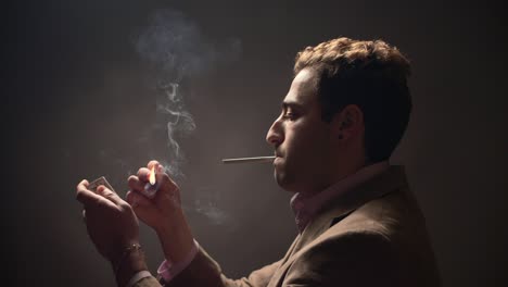 young male lights a cigarette with a matchbox and smokes