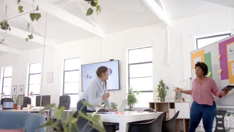 diverse business female colleagues brainstorming using notes and tablet in office, slow motion