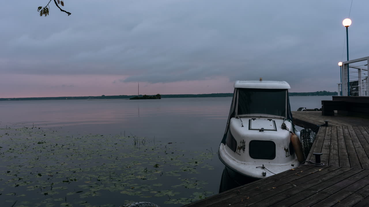 Timelapse: night to day, small white boat docked on a lake at sunrise, outdoor