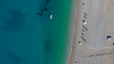 Beach-with-umbrellas-on-sand-washed-by-azure-sea-water-in-Mediterranean,-summer-vacation