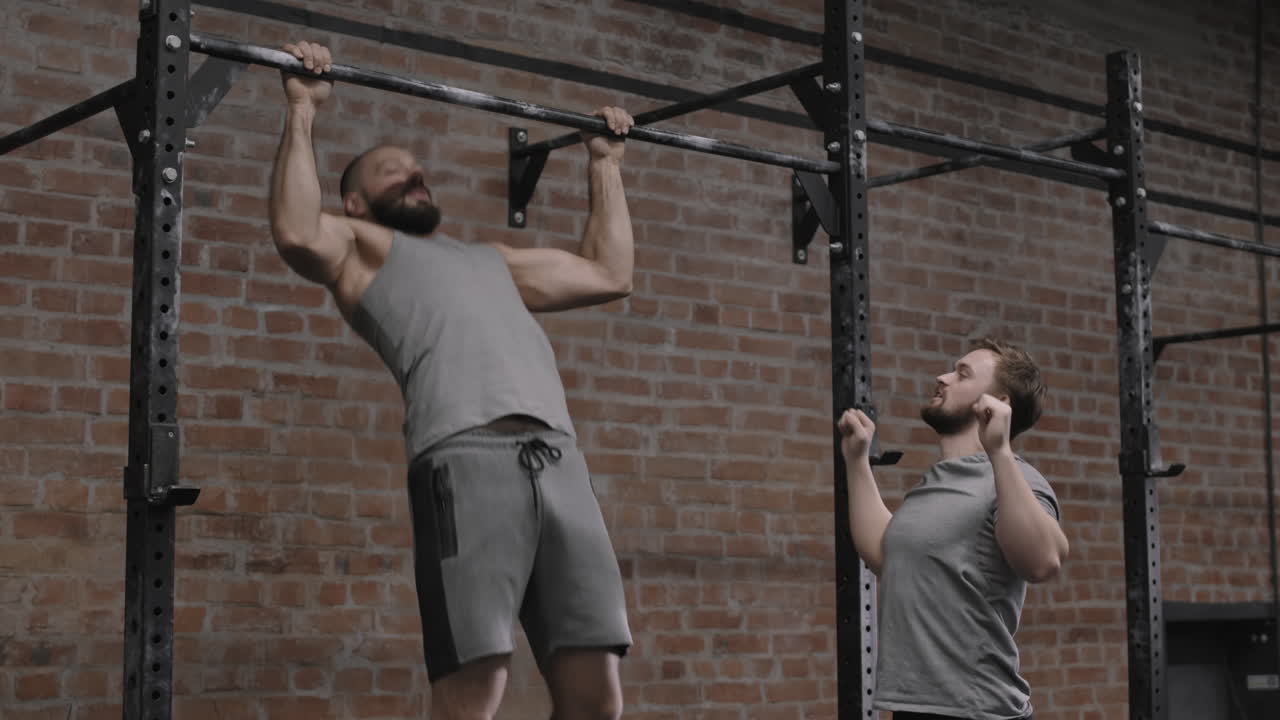 Coach Watching Man Exercising on Horizontal Bar