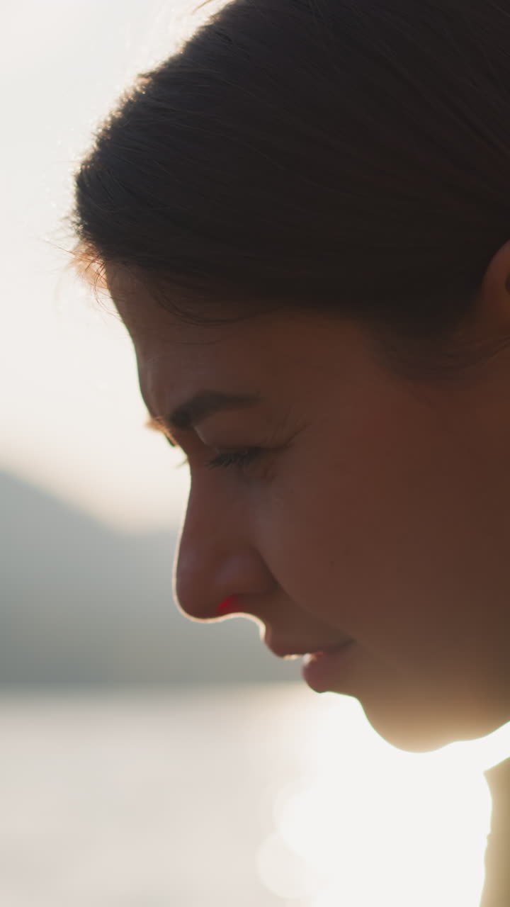 mujer sentada en el banco al atardecer. mujer molesta pensando en acontecimientos tristes en la vida con vistas al lago y las montañas en un clima soleado. dolor de estar sola rodeada de belleza natural