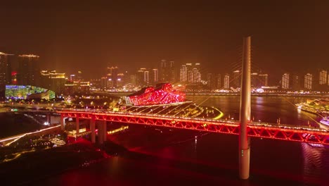a vibrant night scene of a bridge in chongqing, china, with a theater structure lit up in red. the city skyline gleams in the background, showcasing the city's modern architecture and dynamic energy.