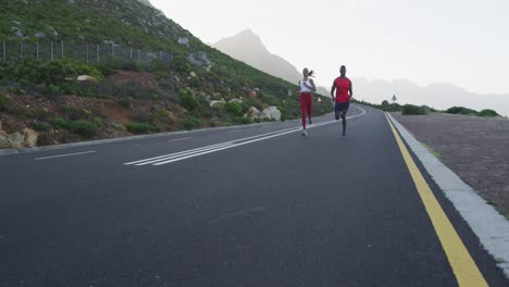 diverse fit couple exercising running on a country road near mountains