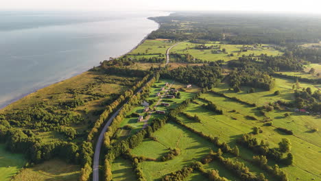 winding country road, vibrant rural landscape and coastline on sunny day, aerial view