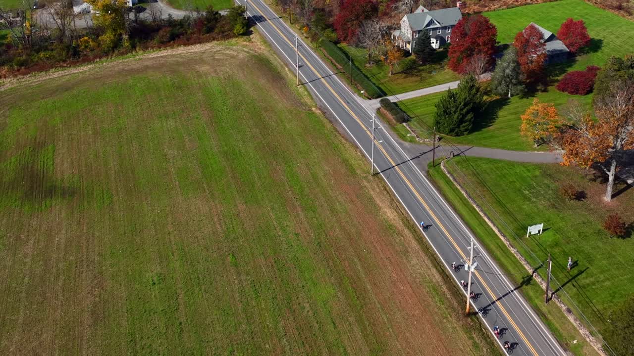 una vista aérea de una carretera de dos carriles en una zona rural de nueva jersey con tierras de cultivo y grandes campos verdes en un día soleado