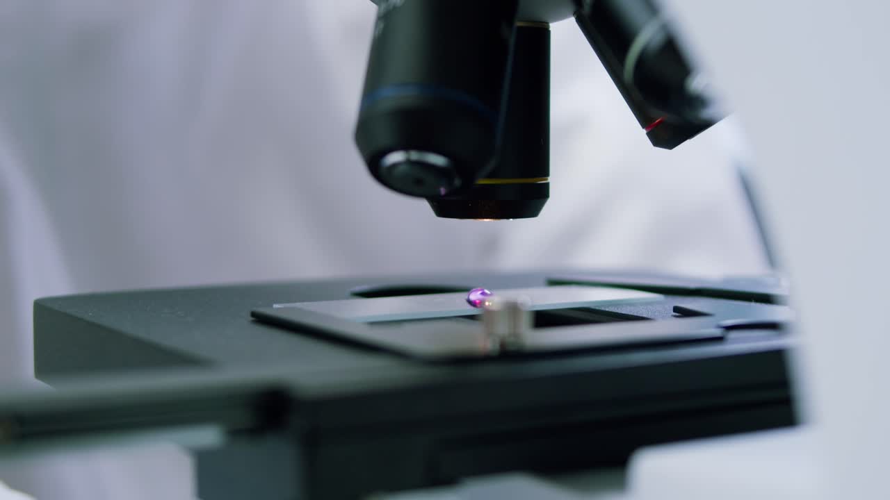 Close-up of Scientist Adjusting Microscope in Laboratory