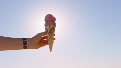 close up hand woman holding ice cream dessert on beatiful sunny beach enjoying summer vacation eating soft serve