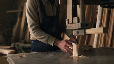 Slow-motion-footage-of-carpenter-working-with-a-wood-block-in-workshop.-Electric-saw.-Wooden-furniture-behind