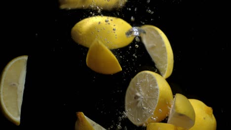 slices of lemon falling into the water with air bubbles.