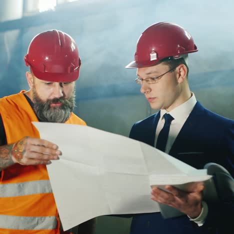 Dos-Ingenieros-Estudian-Dibujos-Trabajan-En-El-Almacén-1