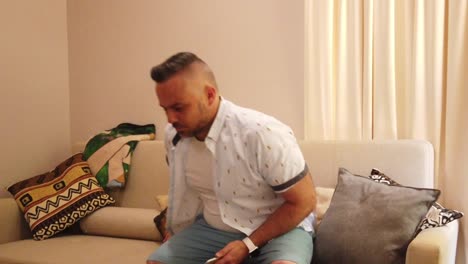 disparo medio del hombre sentado en un cómodo sofá poniendo la televisión en sus piernas hacia arriba, cámara lenta