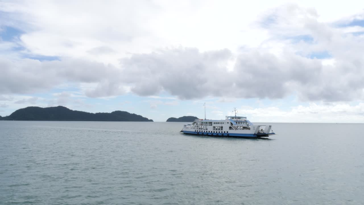 Ferry on calm sea heading to Koh Chang under cloudy sky in Thailand