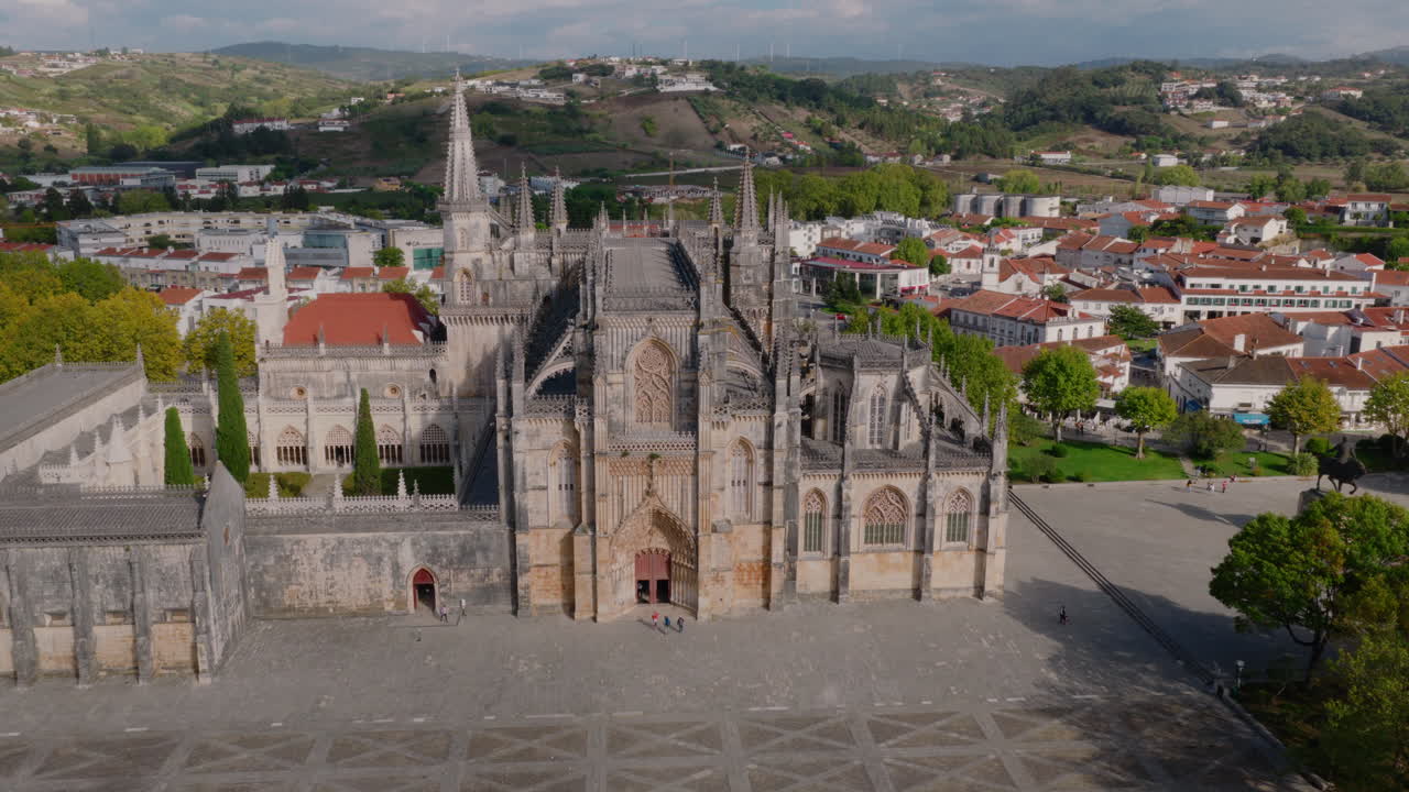 Mosteiro da Batalha aerial pull‑back, expanding reveal from complex to surrounding plaza and townscape