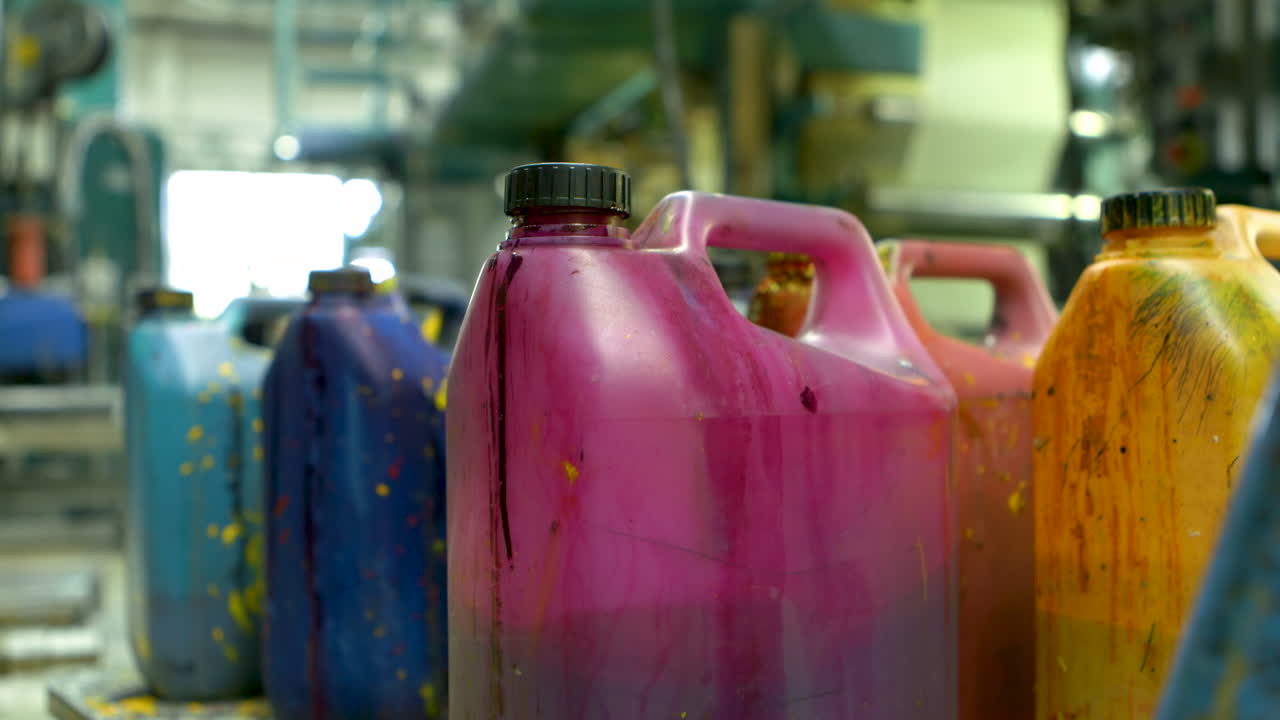 Closeup of a group of paint-splatterd containers. A male hand appears and removes one container.