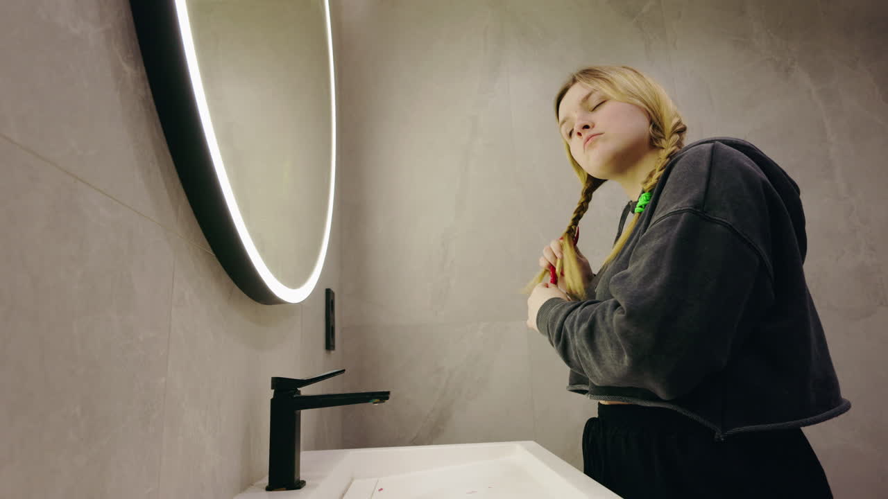Teenager in bathroom, doing hair