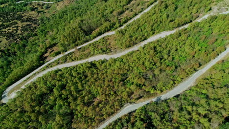 aerial curved mountain pass road through the forest nature landscape drone footage