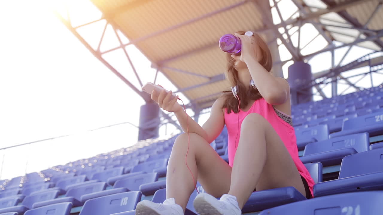 경기장에서 휴식을 취하고 수분을 섭취하는 여성