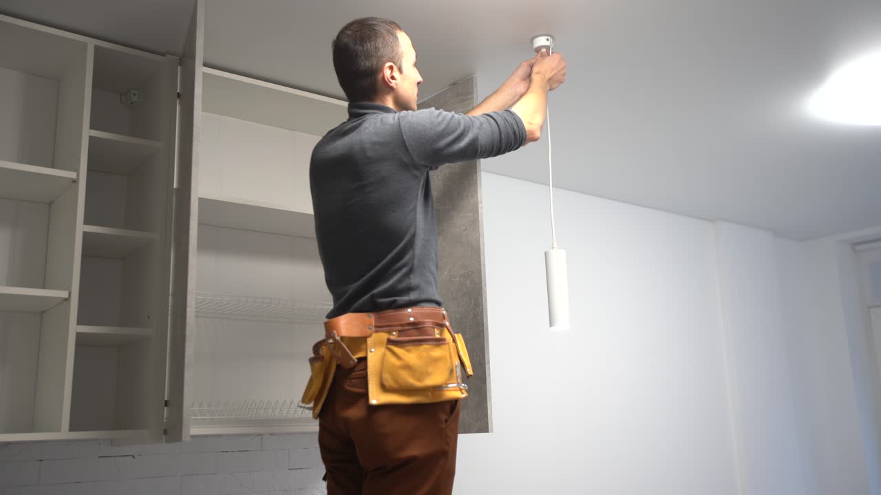 Electrician in the house after repair installs a lamp