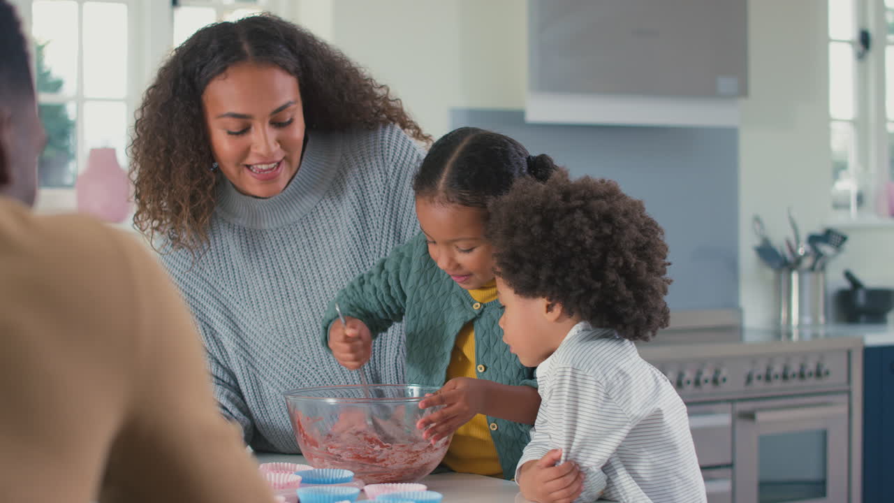 familia con niños en la cocina mezclando ingredientes para pasteles