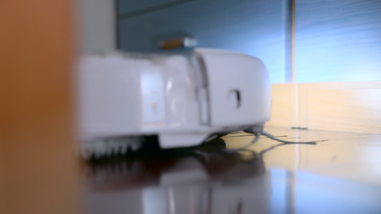 Sleek white robot vacuum glows with a bright front light, ready to clean floors in a modern home