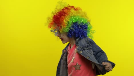 little child girl clown in colorful wig making silly faces. having fun, singing, dancing. halloween