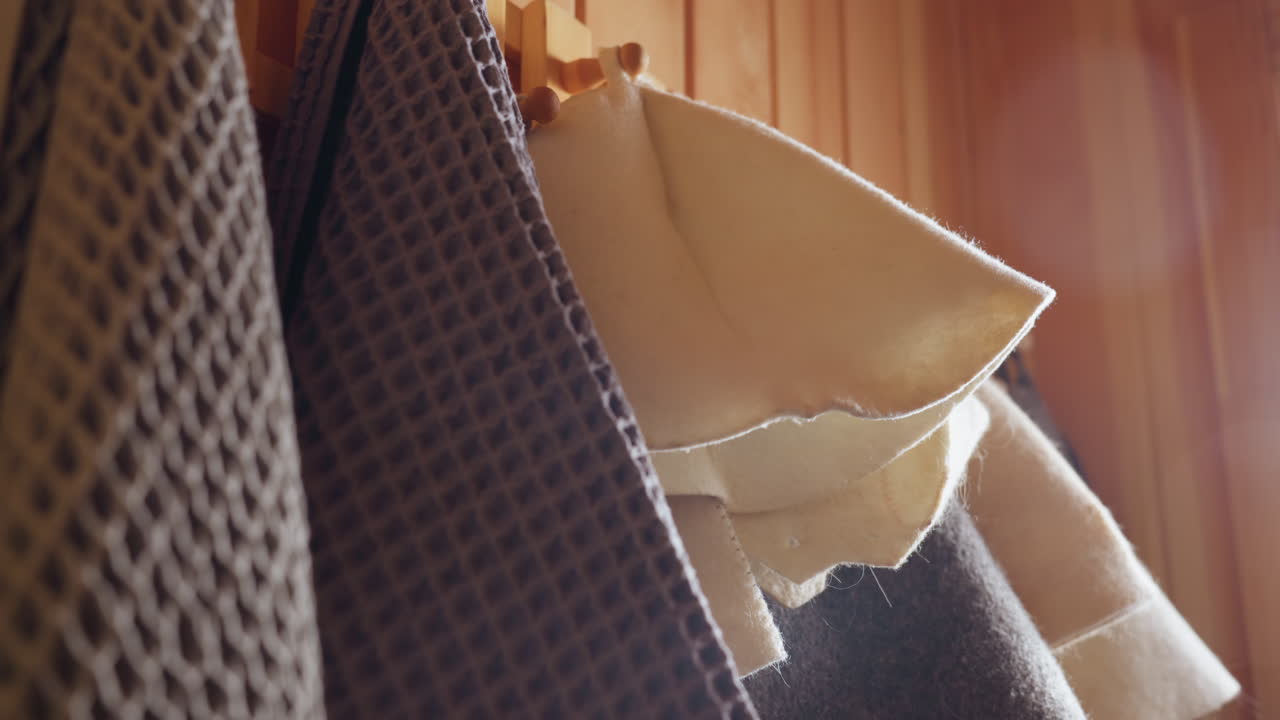 Close up of sun hat with gentle curves hanging beside towel in warmly lit room, highlighting delicate fabric texture, natural beige color, and peaceful indoor ambiance with soft unfocused background
